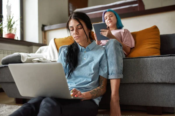 Menina Usando Tablet Digital Sofá Enquanto Sua Namorada Trabalhando Estudando — Fotografia de Stock