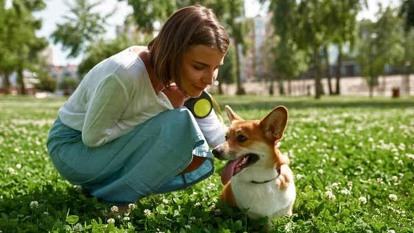 Młoda Uśmiechnięta Biała Dziewczyna Pieści Swojego Pięknego Psa Corgi Zielonej — Zdjęcie stockowe