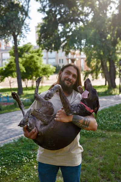 Улыбающийся Европейский Мужчина Держит Руках Свою Очаровательную Собаку Куржаар Смотрит — стоковое фото