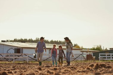Genç, mutlu, beyaz bir aile çiftlikte ya da çiftlikte çiftçilik yapıyor. Anne, baba, kız ve oğul birlikte vakit geçiriyorlar. Modern hippi kırsal yaşam tarzı. Tarım. Güneşli bir gün