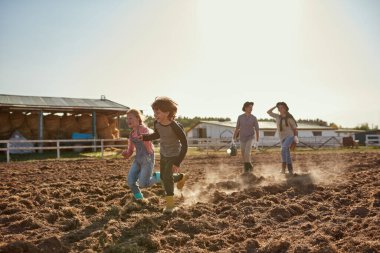 Kızları ve oğulları çiftlikte ya da çiftlikte tarla sürerken kadın ve erkek yürürler. Genç, mutlu, beyaz bir aile birlikte vakit geçiriyor. Modern hippi kırsal yaşam tarzı. Tarım. Güneşli bir gün