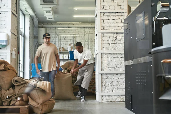 Młodzi Wielorasowi Pracownicy Niosący Worek Tekstylny Ziarnem Kawy Fabryce Proces — Zdjęcie stockowe