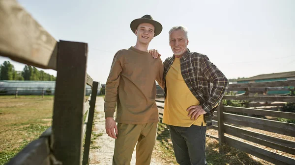 Літній Чоловік Фермер Його Онук Підліток Обіймаються Дивляться Камеру Фермі — стокове фото