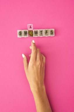 Açılmış plastik paketten marihuana tomurcuğu alan bir kızın görüntüsü. Hafif uyuşturucu ve bağımlılık. Bitkisel ilaçlar ve ağrı kesici tedavisi. Doğal organik kenevir. Pembe arkaplan