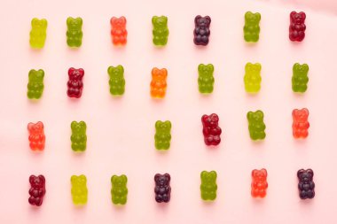 Top view of collection of colorful sweet delicious teddy bear candies in four rows isolated on beige background. Dessert food for kids. Confectionery. Copy space
