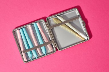 Esrarın sigara tabakasında sarılmış halinin en üst görüntüsü. Yasallaştırılmış uyuşturucu. Bitkisel ilaçlar ve ağrı kesici tedavisi. Doğal ev yapımı organik kenevir. Uyuşturucu satıcılığı. Pembe arka planda izole edilmiş. Boşluğu kopyala