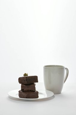 Kahve ve taze yeşil, ezilmiş marihuana tomurcuğu tabakta lezzetli çikolatalı kek parçaları. Hafif uyuşturucu ve bağımlılık. Doğal organik kenevir. Beyaz arka plan. Boşluğu kopyala