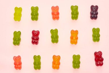 Top view of set of colorful sweet delicious teddy bear candies in three rows isolated on beige background. Dessert food for kids. Confectionery