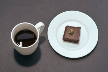 Kahveli ve taze yeşil, ezilmiş marihuana tomurcuklu tatlı çikolatalı kek tabağında. Hafif uyuşturucu ve bağımlılık. Doğal organik kenevir. Koyu gri arka planda izole edilmiş. Boşluğu kopyala