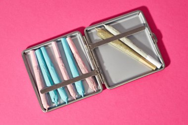 Esrarın sigara tabakasında sarılmış halinin en üst görüntüsü. Yasallaşmış hafif uyuşturucu. Bitkisel ilaçlar ve ağrı kesici tedavisi. Doğal organik kenevir. Uyuşturucu satıcılığı. Pembe arka planda izole edilmiş. Boşluğu kopyala