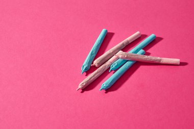 Collection of cannabis rolled joints isolated on pink background. Legalized light drug and addiction. Herbal medicine and painkiller therapy. Natural organic cannabis. Drug dealing. Copy space