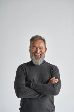 Kollarını kavuşturup kameraya bakan yaşlı, beyaz bir adamın ön görüntüsü. Süveter giyen modaya uygun sakallı bir emekli. Modern son sınıf erkek yaşam tarzı. Beyaz arka plan. Stüdyo çekimi. Boşluğu kopyala