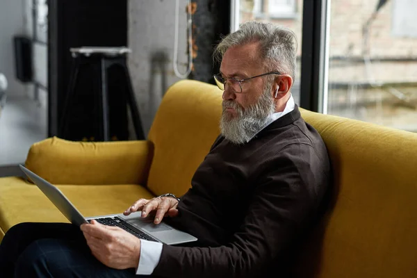 Elderly Caucasian Man Using Watching Laptop Sofa Spacious Apartment Trendy — Stockfoto