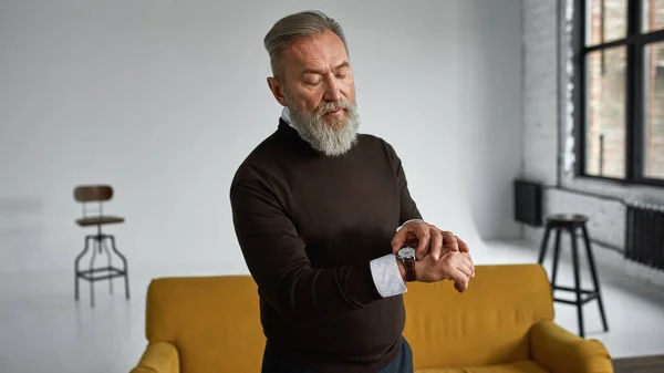 Grey Hair Focused Caucasian Man Watching Time Wristwatch Spacious Apartment — Stockfoto