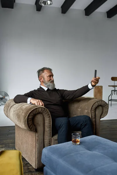 Elderly Caucasian Man Resting Taking Selfie Smartphone Armchair Spacious Apartment — Stockfoto