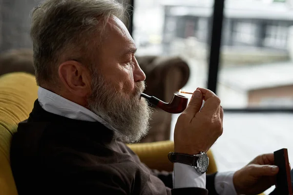 Grey Hair Focused Caucasian Man Lighting Tobacco Pipe Match Sofa — Stockfoto
