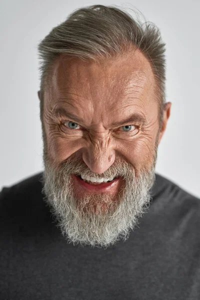 Portrait of senior angry caucasian man looking at camera. Stylish bearded pensioner wearing casual clothes. Concept of modern elderly male lifestyle. Isolated on white background. Studio shoot