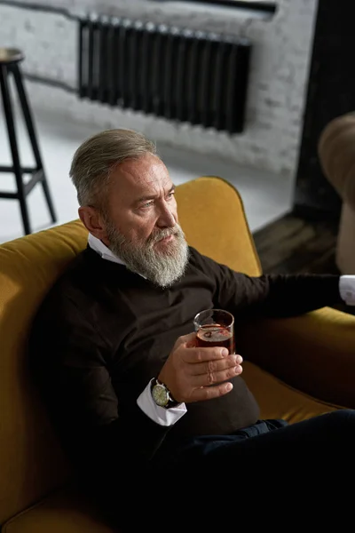 Elderly Thoughtful Caucasian Man Drinking Whiskey Brandy Sofa Spacious Apartment — Fotografia de Stock