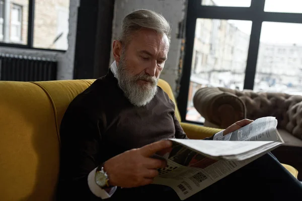 Senior Focused Caucasian Man Reading Newspaper Sofa Home Stylish Bearded — Foto Stock