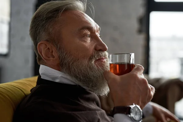 Elderly Thoughtful Caucasian Man Drinking Whiskey Cognac Sofa Spacious Apartment — Fotografia de Stock