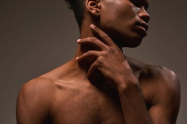 Partial image of african american handsome guy posing on brown background. Obscure face of young brunette man with naked torso. Concept of modern male beauty. Studio shoot