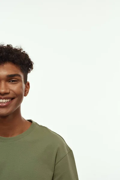 Obscure face of smiling black handsome guy looking at camera. Cropped brunette curly man wearing t-shirt. Concept of modern young male lifestyle. Isolated on white background. Studio shoot. Copy space