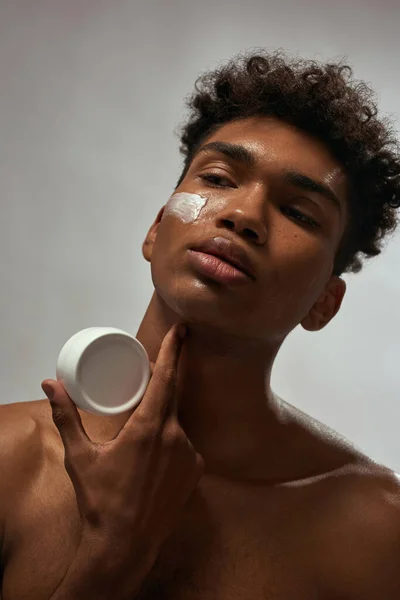 Partial Thoughtful Black Guy Cream Face Holding Container Cosmetic Cream — Stockfoto