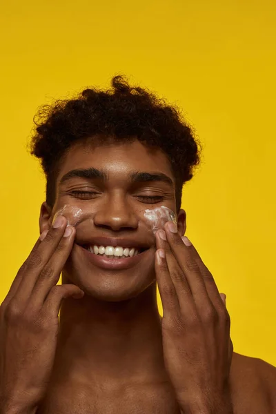 Sebagian Tersenyum African American Pria Mengolesi Krim Kosmetik Wajahnya Pemuda — Stok Foto
