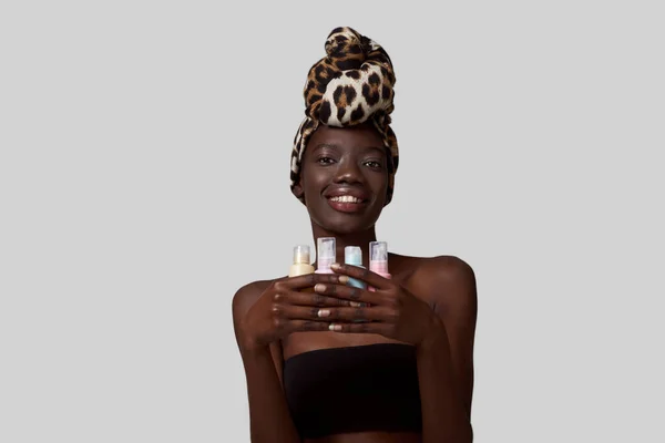 Smiling Elegant Black Girl Holding Four Colorful Nail Polishes Beautiful — Stockfoto