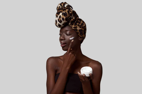 Stylish Black Girl Smearing Cosmetic Cream Container Her Face Young — Stockfoto