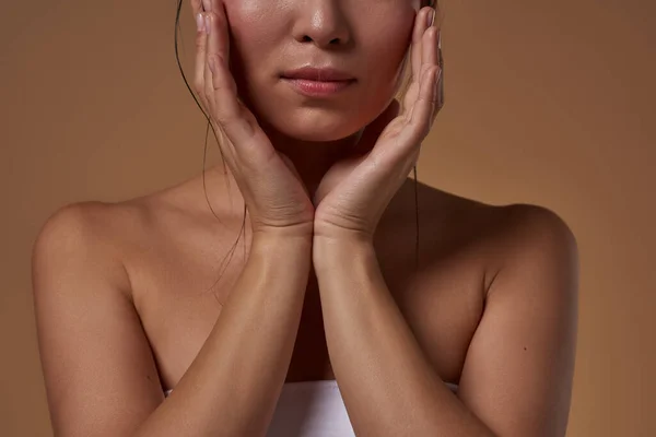Cropped of elegant asian girl touching her head. Obscure face of beautiful young slim woman wearing tank top. Female beauty. Isolated on orange background. Studio shoot