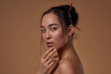 Cropped image of elegant japanese or chinese girl looking at camera. Beautiful young brunette slim woman. Female beauty. Isolated on orange background. Studio shoot. Copy space