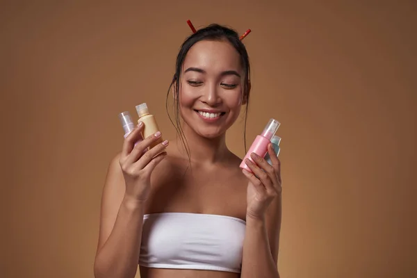 Smiling Asian Girl Holding Looking Four Colorful Nail Polishes Pretty — Foto de Stock