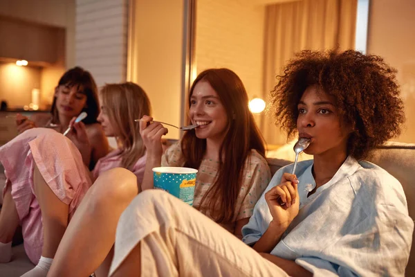 Young Multiracial Girlfriends Eating Ice Cream Watching Movie Sofa Girlish — Stockfoto