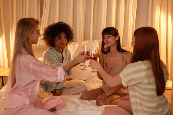 Young Multiethnic Girlfriends Toasting Drinking Wine Bed Girlish Sleepover Night — Foto de Stock