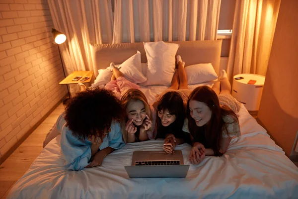 Young Laughing Multiethnic Girlfriends Watching Laptop Bed Girlish Sleepover Party —  Fotos de Stock