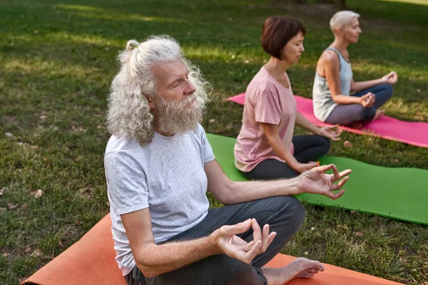 Three Concentrated Senior Caucasian Friends Meditating Practicing Yoga Lotus Pose — Zdjęcie stockowe