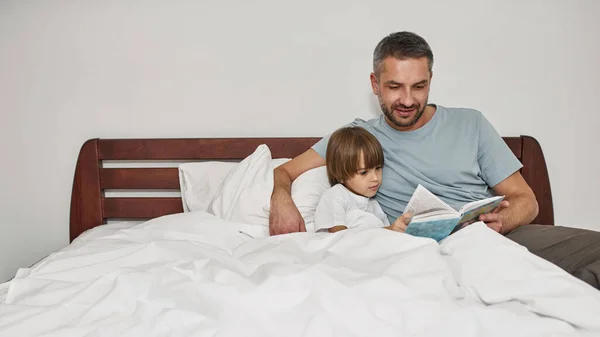 父と息子は家で本を読んでいる 若い白人の家族関係と一緒に時間を過ごす 父親と子育て 国内レジャー — ストック写真