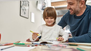 Baba bak evdeki masada keçeli kalemle keçeli kalem çiziyor. Gülümseyen beyaz adam ve küçük çocuk birlikte eğleniyorlar. Babalık ve ebeveynlik. Ev eğlencesi, hobi ve eğlence