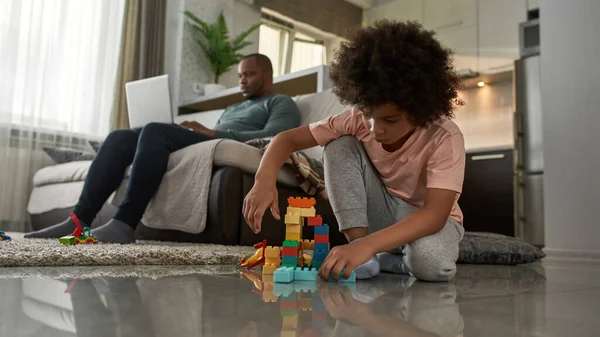 Malý Chlapec Hraje Stavebními Bloky Podlaze Zatímco Jeho Otec Používá — Stock fotografie