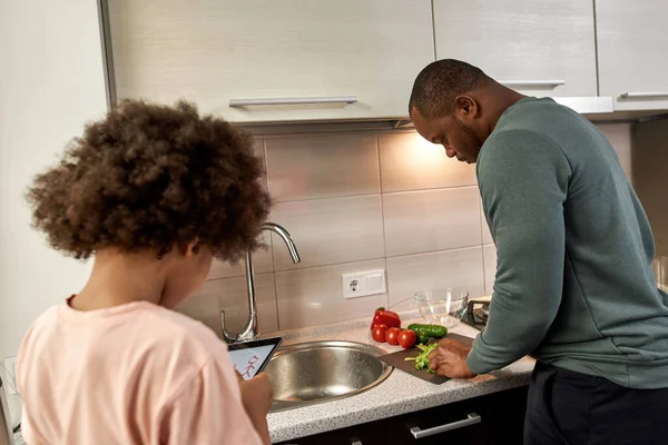 Niño Negro Dibujando Humanos Una Tableta Digital Mientras Padre Cocinaba —  Fotos de Stock