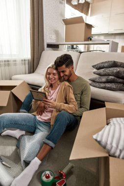 Genç ve çok ırklı çift, karton kutuya bir şeyler koyarken dinleniyor ve yere bakıyor. Orta Doğulu bir adam ve sarışın beyaz bir kadın yeni bir daireye taşınıyor. Ev Taşıması