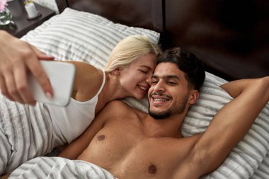 Genç ve çok ırklı bir çift evlerinde akıllı telefonlarıyla selfie çekiyor. Beyaz kız ve Orta Doğulu adam dinleniyor ve birlikte vakit geçiriyorlar. Ev eğlencesi ve eğlence. Sabah oldu.