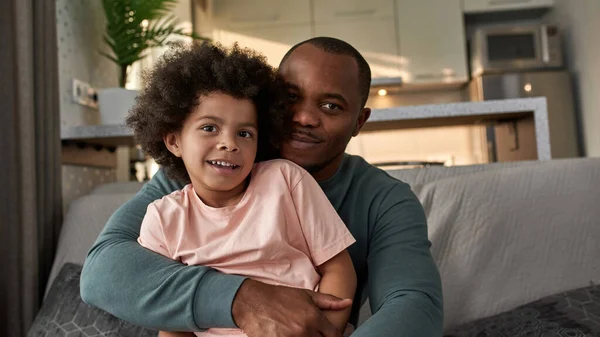 Dospělý Otec Objímá Svého Malého Syna Doma Gauči Usmívající Černoch — Stock fotografie