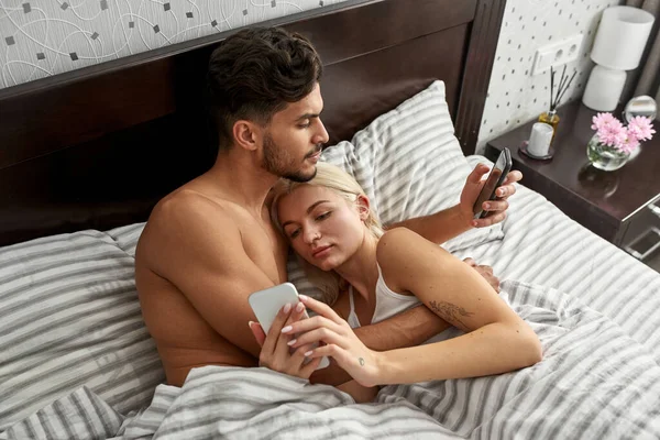 침대에서 스마트폰을 사용하는 집중적 친구의 현실적으로 — 스톡 사진