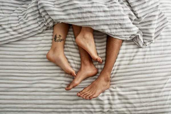 Snímek Bosých Nohou Muže Ženy Tetováním Ležících Pod Přikrývkou Posteli — Stock fotografie