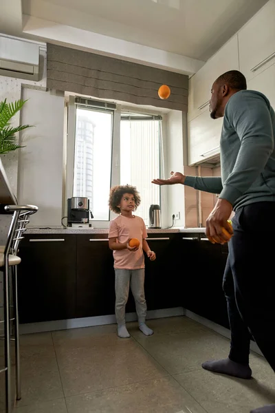 Focuesd Küçük Çocuk Evde Portakallarla Oynayan Babasına Bakıyor Genç Siyahi — Stok fotoğraf