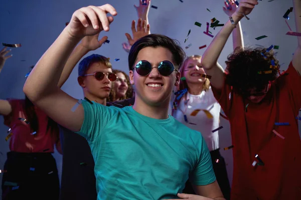 Zadowolony Biały Nastolatek Okularach Tańczący Bawiący Się Przyjaciółmi Latającym Konfetti — Zdjęcie stockowe