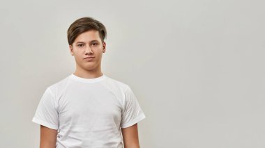 Kameraya bakan beyaz bir gencin kısmi görüntüsü. Zoomer kuşağından biri tişört giyer. Modern gençlik yaşam tarzı kavramı. Beyaz arka planda izole edilmiş. Stüdyo çekimi. Boşluğu kopyala