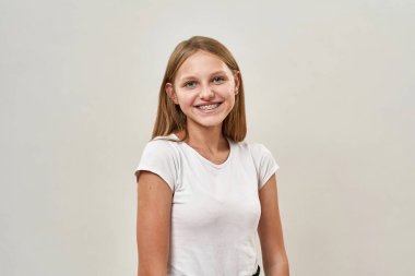 Tel takmış kameraya bakan gülümseyen beyaz kız. Zoomer kuşağının güzel dişi çocuğu. Modern gençlik yaşam tarzı kavramı. Beyaz arka planda izole edilmiş. Stüdyo çekimi. Boşluğu kopyala